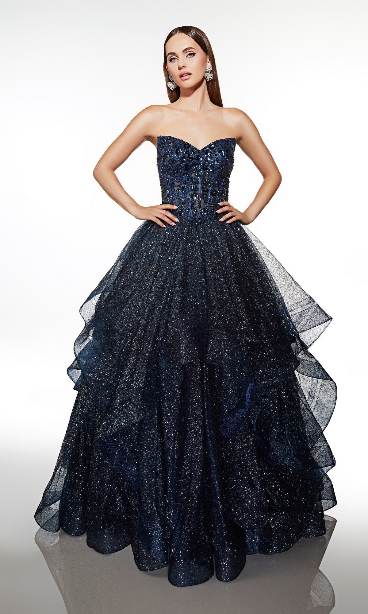 A woman stands against a plain white background wearing the Alyce 62173 long formal dress—a strapless, navy blue ball gown with a fitted bodice and layered glitter tulle skirt.